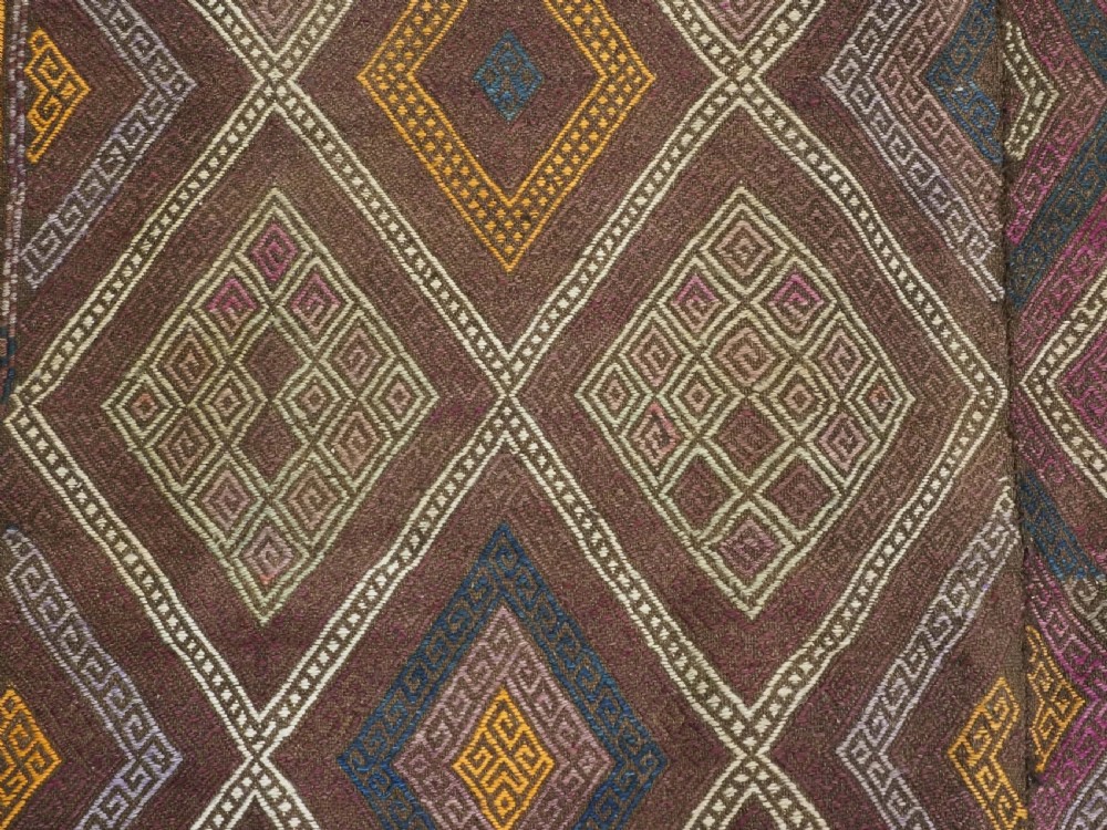 An antique Afghan flatweave wool kilim rug featuring a central brown field filled with geometric diamond motifs framed by patterned borders. View IX
