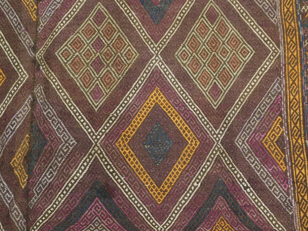 An antique Afghan flatweave wool kilim rug featuring a central brown field filled with geometric diamond motifs framed by patterned borders. View X