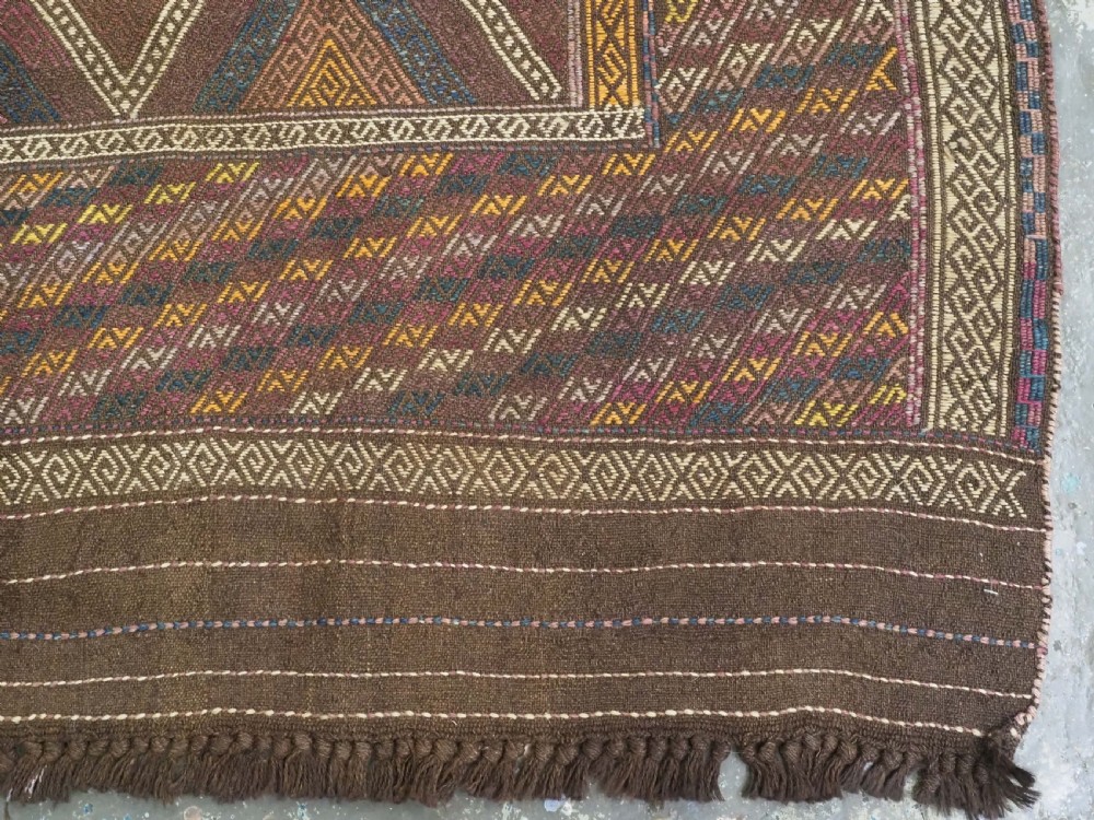 An antique Afghan flatweave wool kilim rug featuring a central brown field filled with geometric diamond motifs framed by patterned borders. View XII