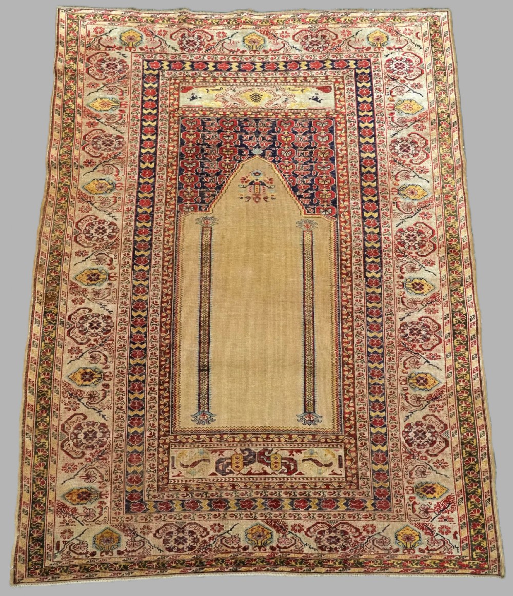 An antique late 19th-century Turkish Kayseri silk prayer rug featuring a central beige mihrab niche surrounded by geometric red and navy borders.