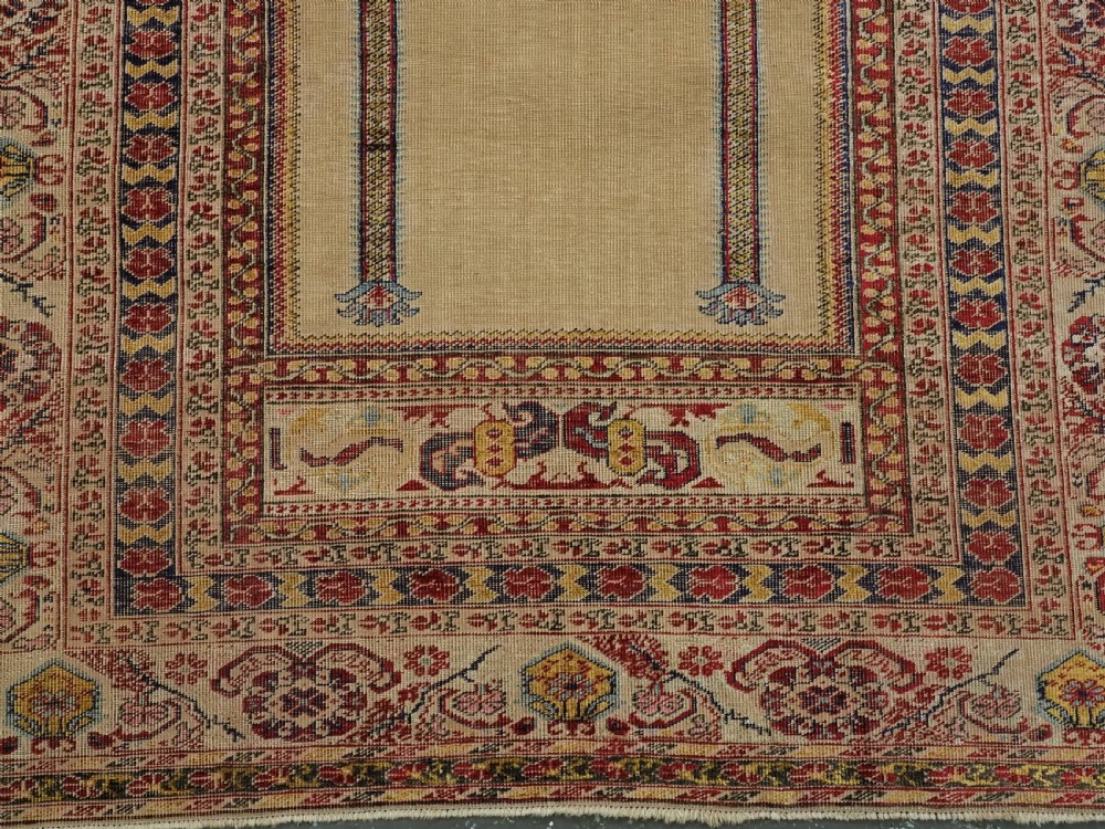An antique late 19th-century Turkish Kayseri silk prayer rug featuring a central beige mihrab niche surrounded by geometric red and navy borders. View X