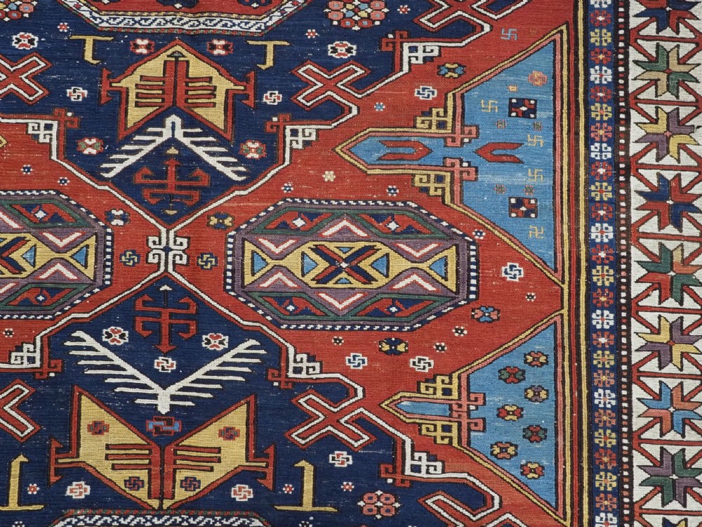 An antique Caucasian Soumak wool flatweave rug featuring three central octagonal medallions surrounded by geometric tribal motifs in red, blue, and yellow. View VIII