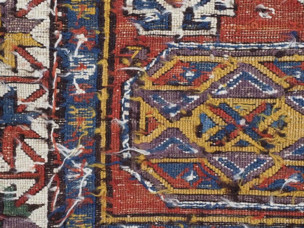 An antique Caucasian Soumak wool flatweave rug featuring three central octagonal medallions surrounded by geometric tribal motifs in red, blue, and yellow. View XII
