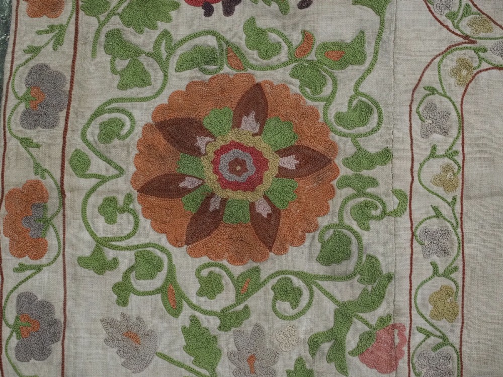 A cream woven cotton textile panel decorated with intricate silk embroidery depicting a pointed arch niche surrounded by floral rosettes and vine tendrils in terracotta and green tones. View VIII