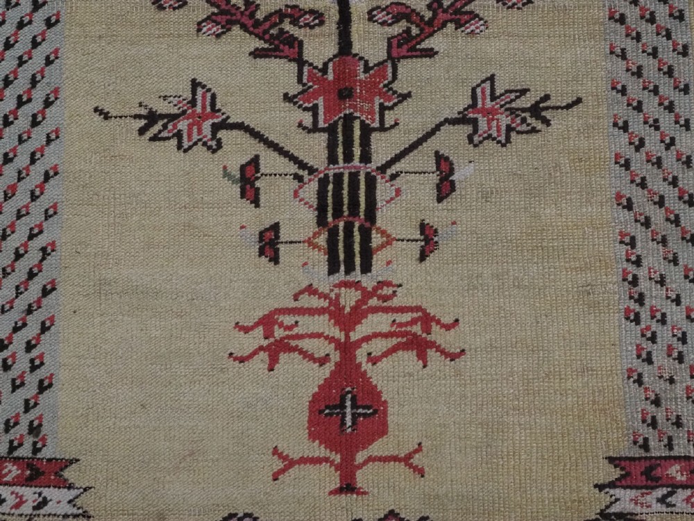 An antique Turkish Kirsehir wool prayer rug featuring a cream central field with a pointed mihrab niche, central tree of life motif, and geometric floral borders in muted red, pink, and green tones. View IX