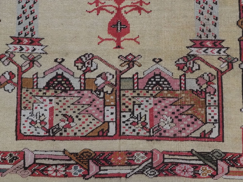 An antique Turkish Kirsehir wool prayer rug featuring a cream central field with a pointed mihrab niche, central tree of life motif, and geometric floral borders in muted red, pink, and green tones. View X