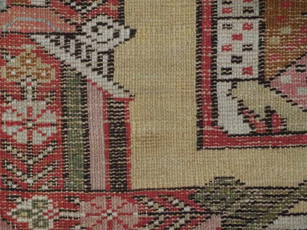 An antique Turkish Kirsehir wool prayer rug featuring a cream central field with a pointed mihrab niche, central tree of life motif, and geometric floral borders in muted red, pink, and green tones. View XII