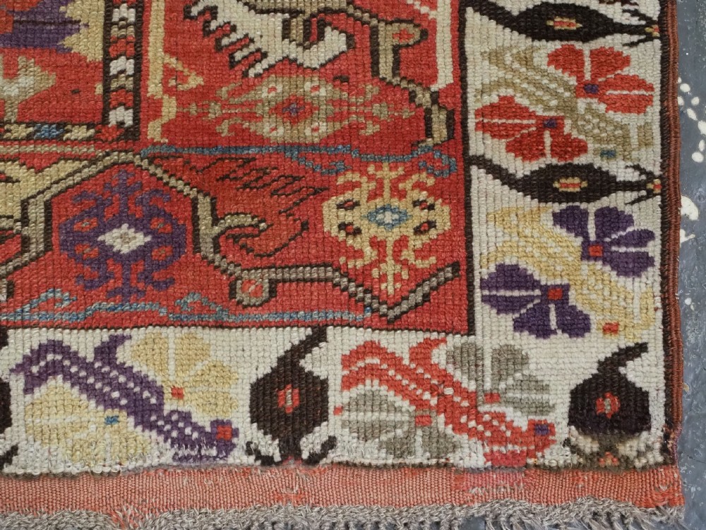 An antique hand-knotted Turkish Milas wool prayer rug featuring a central ivory prayer niche flanked by geometric borders in terracotta, purple, and cream tones. View XII