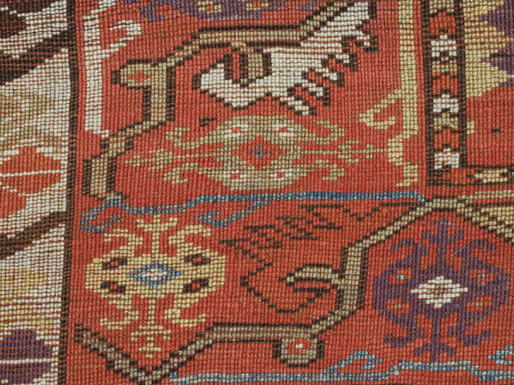 An antique hand-knotted Turkish Milas wool prayer rug featuring a central ivory prayer niche flanked by geometric borders in terracotta, purple, and cream tones. View XIII