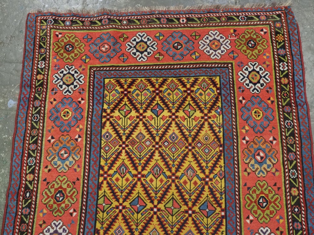 An antique long hand-knotted wool runner rug featuring a yellow lattice pattern field framed by wide red floral geometric borders. View III
