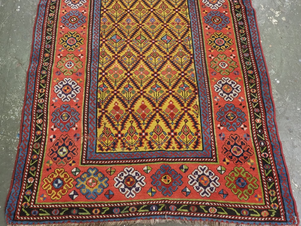 An antique long hand-knotted wool runner rug featuring a yellow lattice pattern field framed by wide red floral geometric borders. View VI