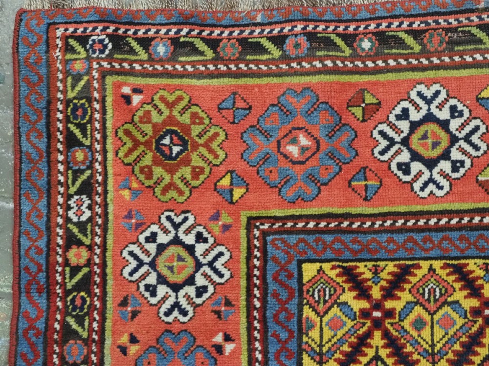 An antique long hand-knotted wool runner rug featuring a yellow lattice pattern field framed by wide red floral geometric borders. View VII