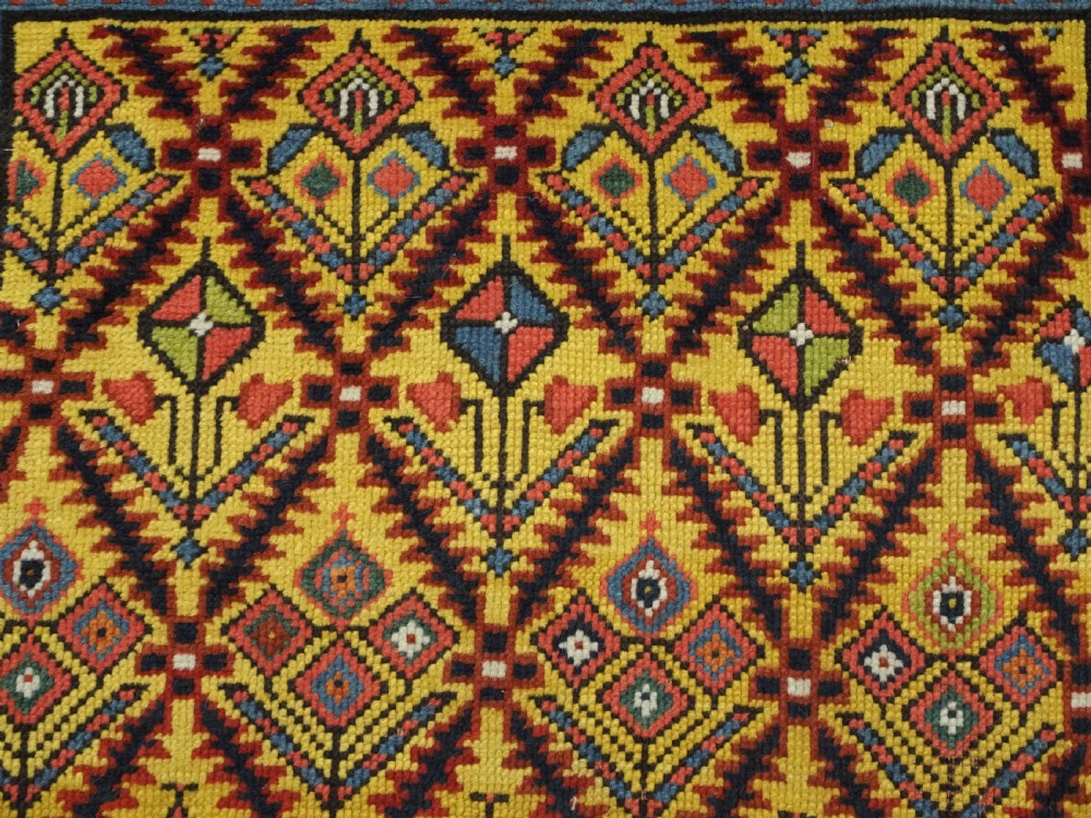 An antique long hand-knotted wool runner rug featuring a yellow lattice pattern field framed by wide red floral geometric borders. View IX