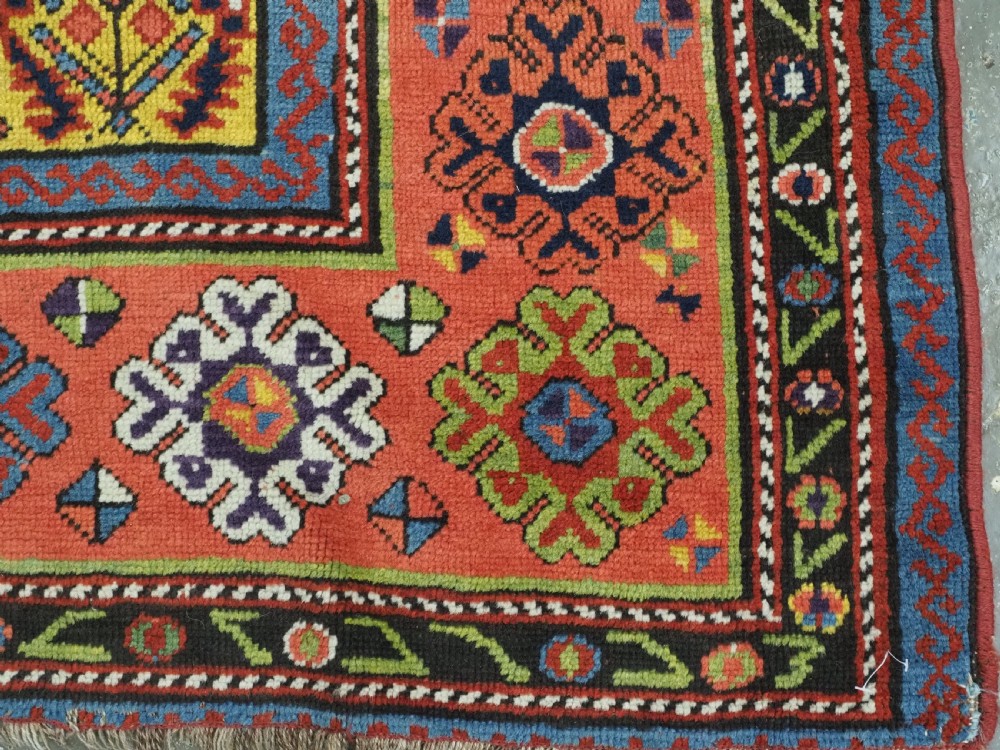 An antique long hand-knotted wool runner rug featuring a yellow lattice pattern field framed by wide red floral geometric borders. View X