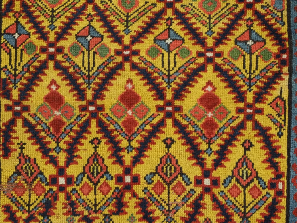 An antique long hand-knotted wool runner rug featuring a yellow lattice pattern field framed by wide red floral geometric borders. View XII