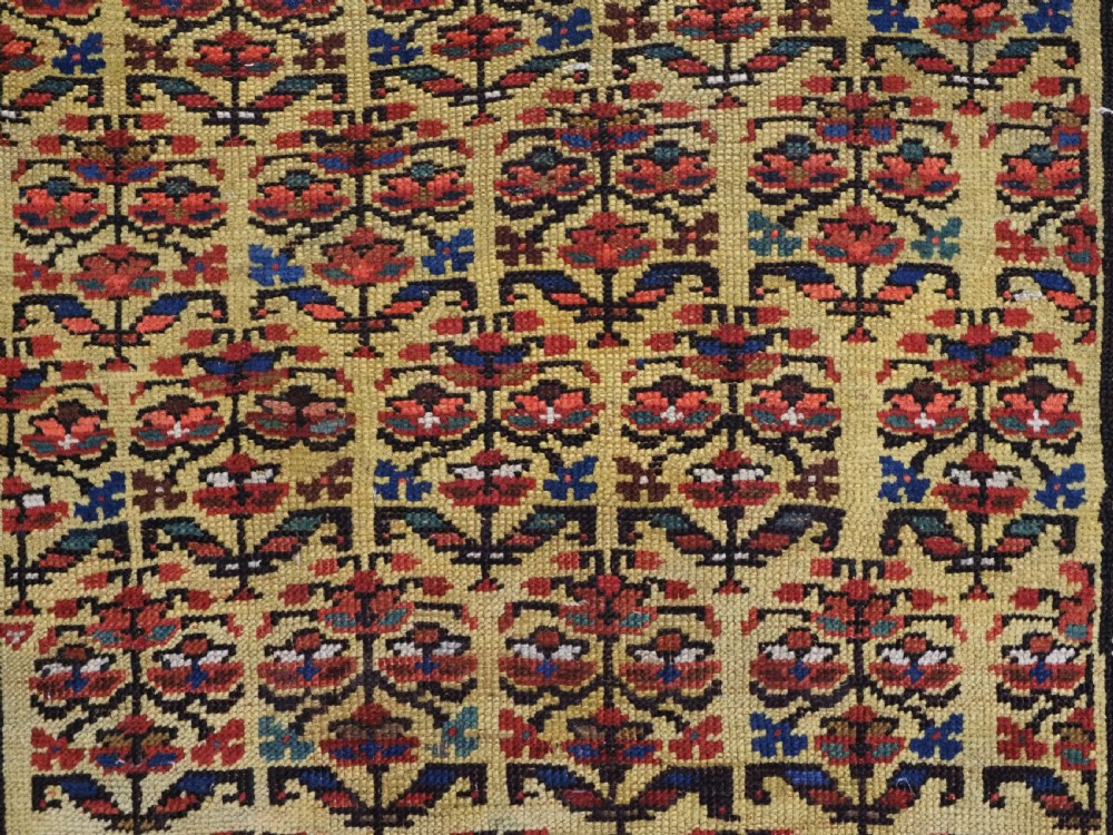An antique hand-knotted Kurdish wool rug featuring a bright yellow central field with repeating red and blue shrub motifs enclosed within patterned borders. View IX