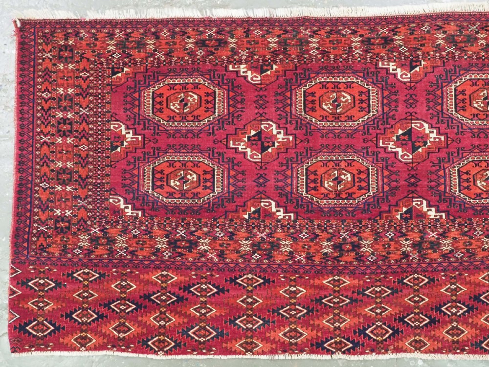 A hand-knotted deep red wool Turkmen chuval face featuring six octagonal Salor guls and a geometric bottom elem border. View II