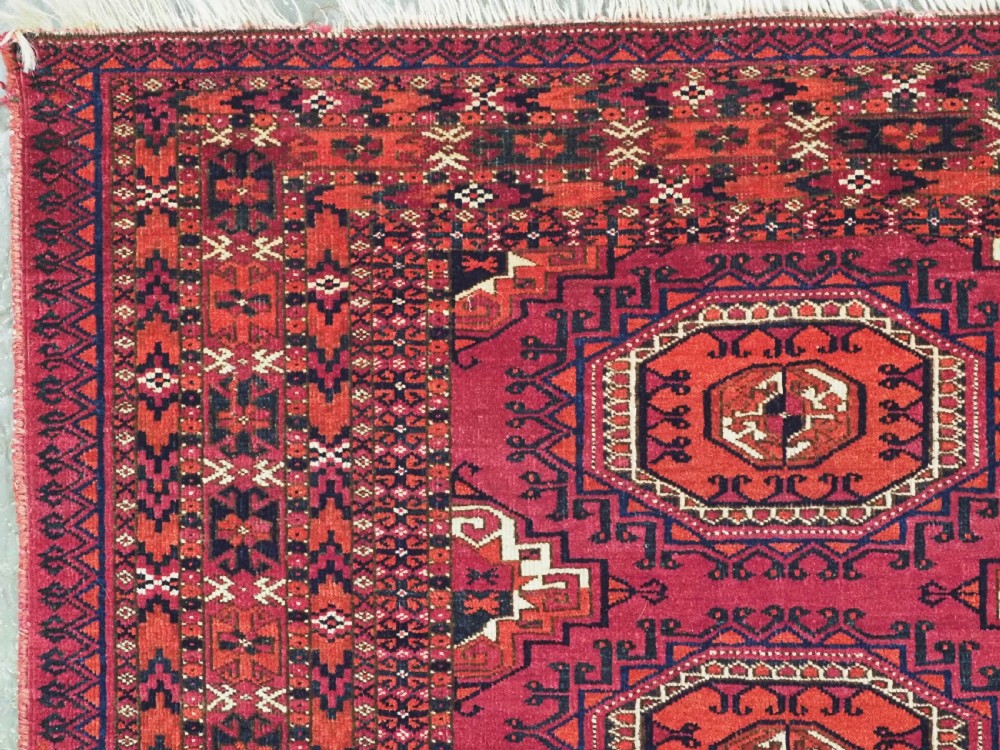 A hand-knotted deep red wool Turkmen chuval face featuring six octagonal Salor guls and a geometric bottom elem border. View III