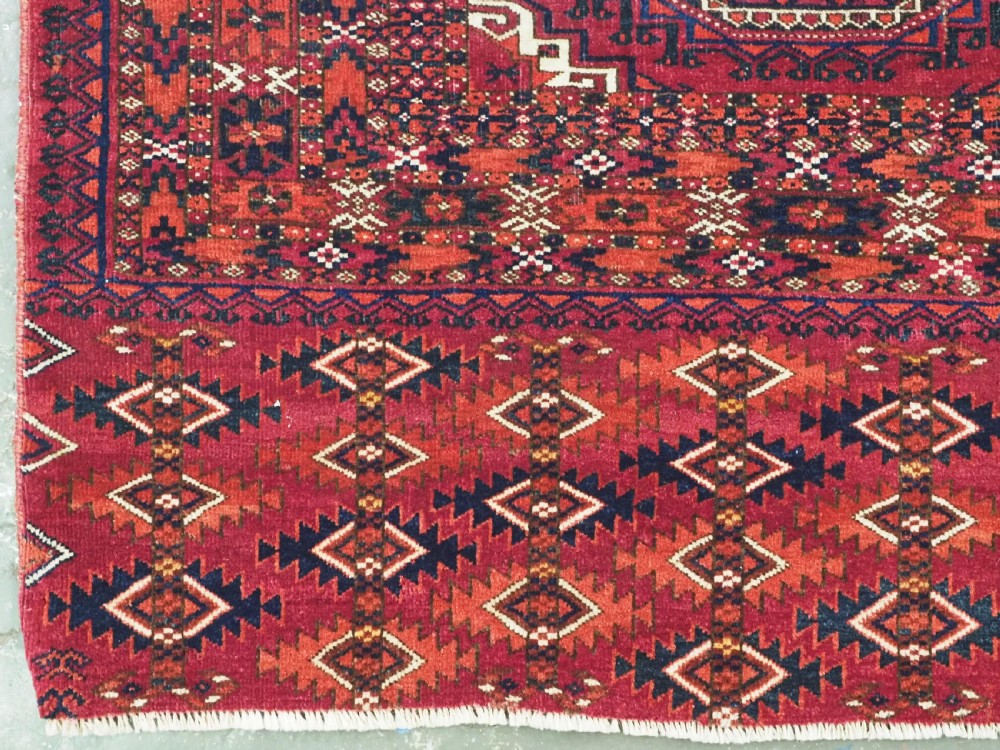A hand-knotted deep red wool Turkmen chuval face featuring six octagonal Salor guls and a geometric bottom elem border. View V