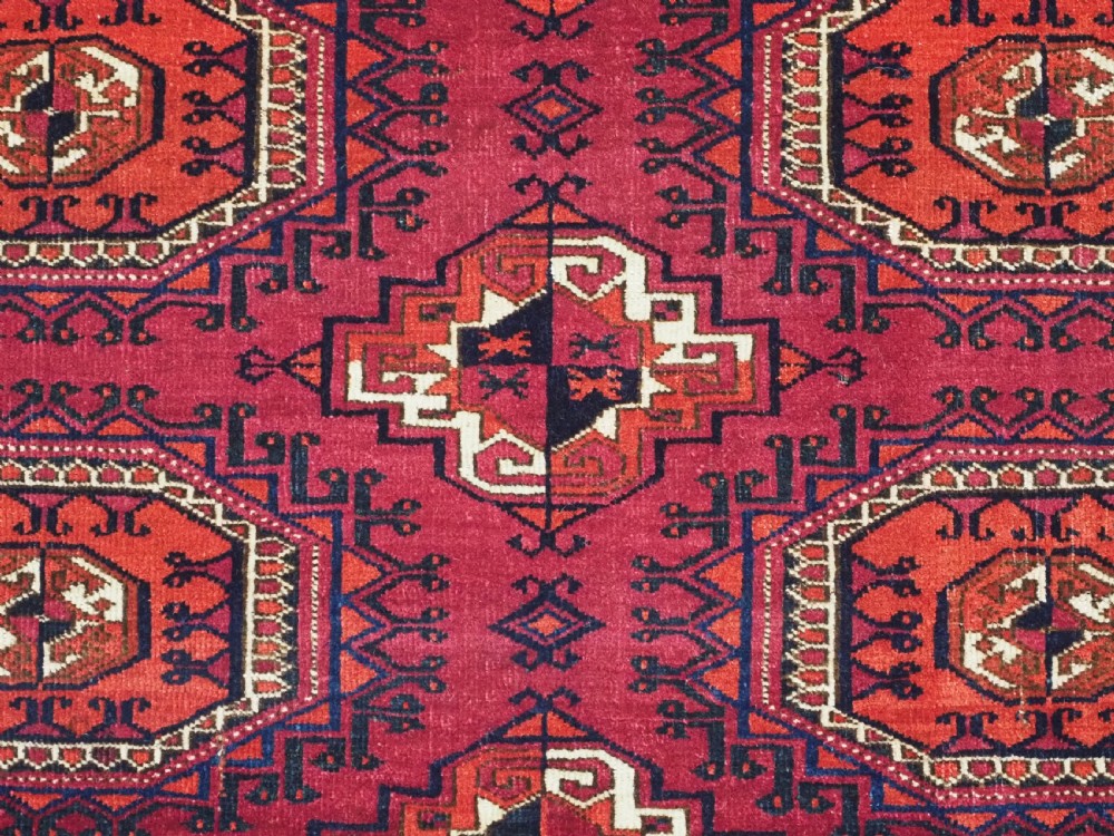 A hand-knotted deep red wool Turkmen chuval face featuring six octagonal Salor guls and a geometric bottom elem border. View VII