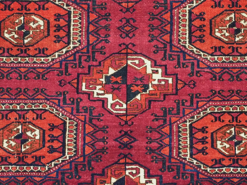 A hand-knotted deep red wool Turkmen chuval face featuring six octagonal Salor guls and a geometric bottom elem border. View VIII