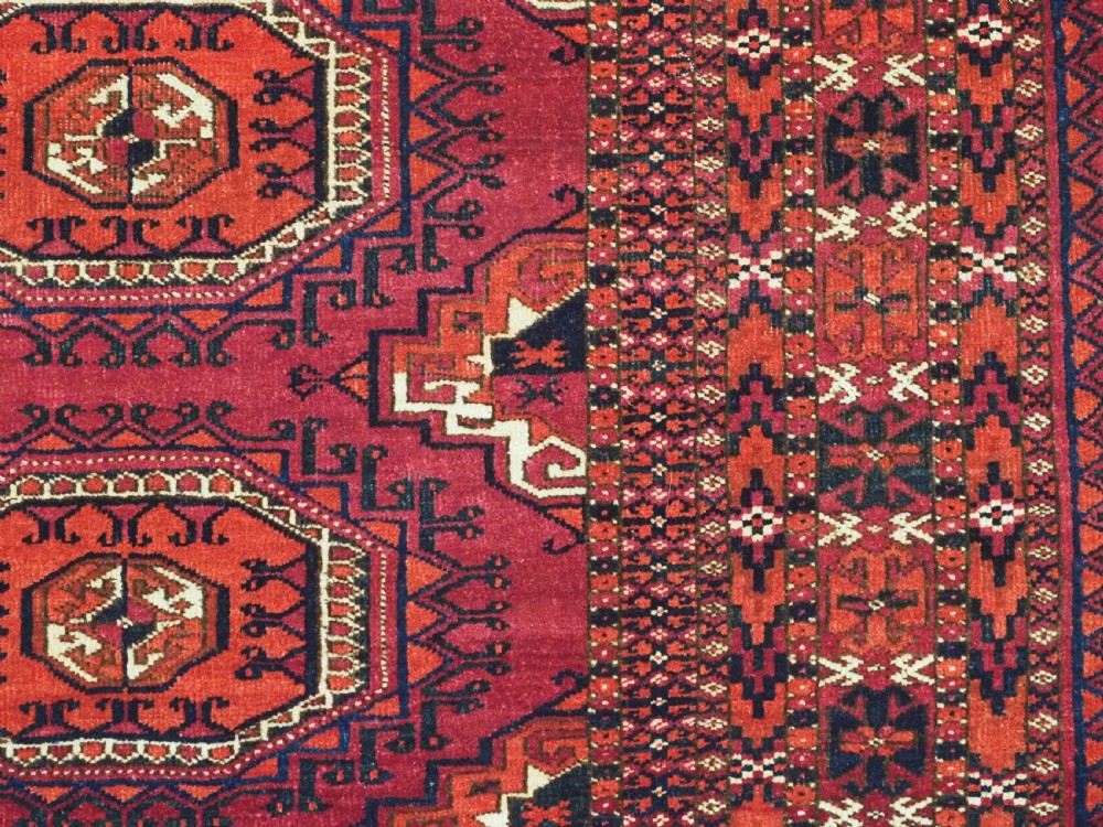 A hand-knotted deep red wool Turkmen chuval face featuring six octagonal Salor guls and a geometric bottom elem border. View X