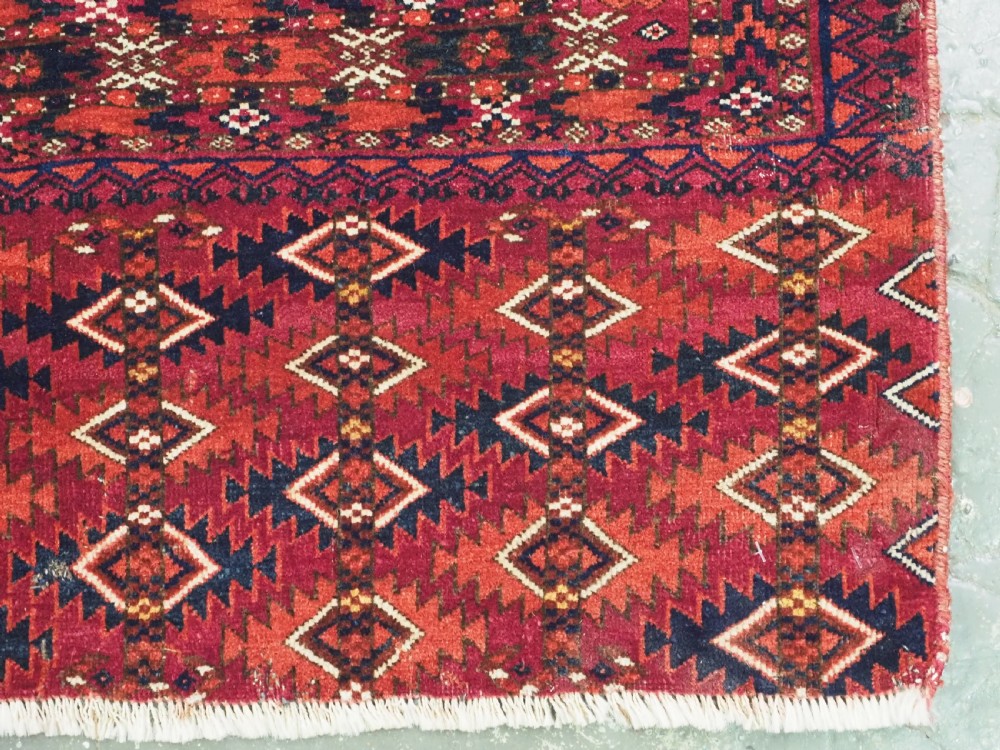 A hand-knotted deep red wool Turkmen chuval face featuring six octagonal Salor guls and a geometric bottom elem border. View XI