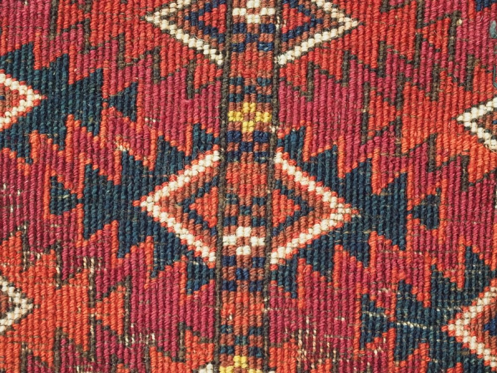 A hand-knotted deep red wool Turkmen chuval face featuring six octagonal Salor guls and a geometric bottom elem border. View XII