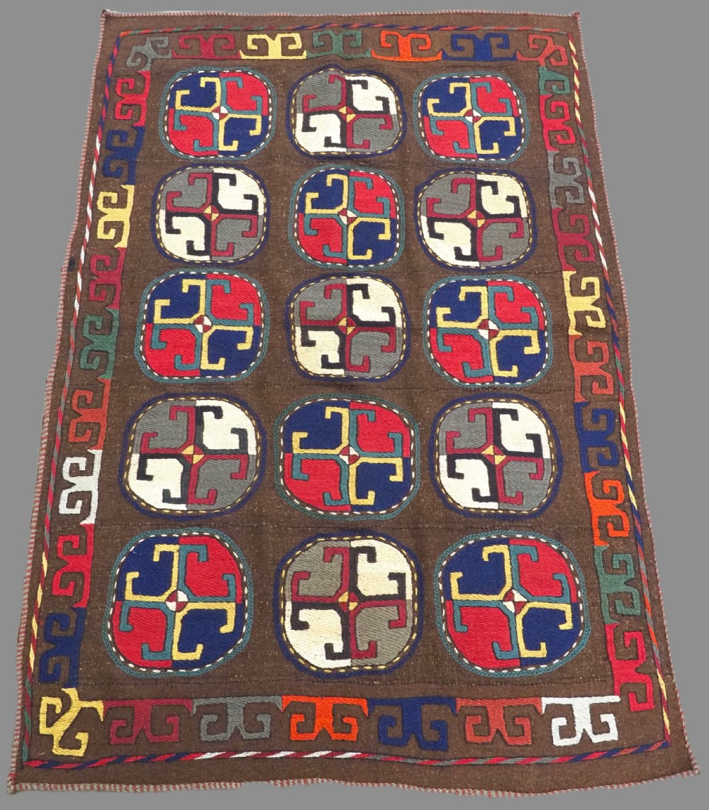 An antique brown camel hair flatweave kilim rug featuring fifteen circular embroidered medallions filled with colourful geometric motifs within a decorative hooked border.