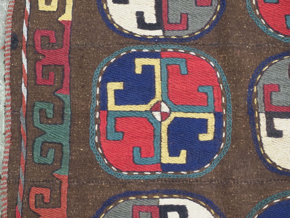An antique brown camel hair flatweave kilim rug featuring fifteen circular embroidered medallions filled with colourful geometric motifs within a decorative hooked border. View VI