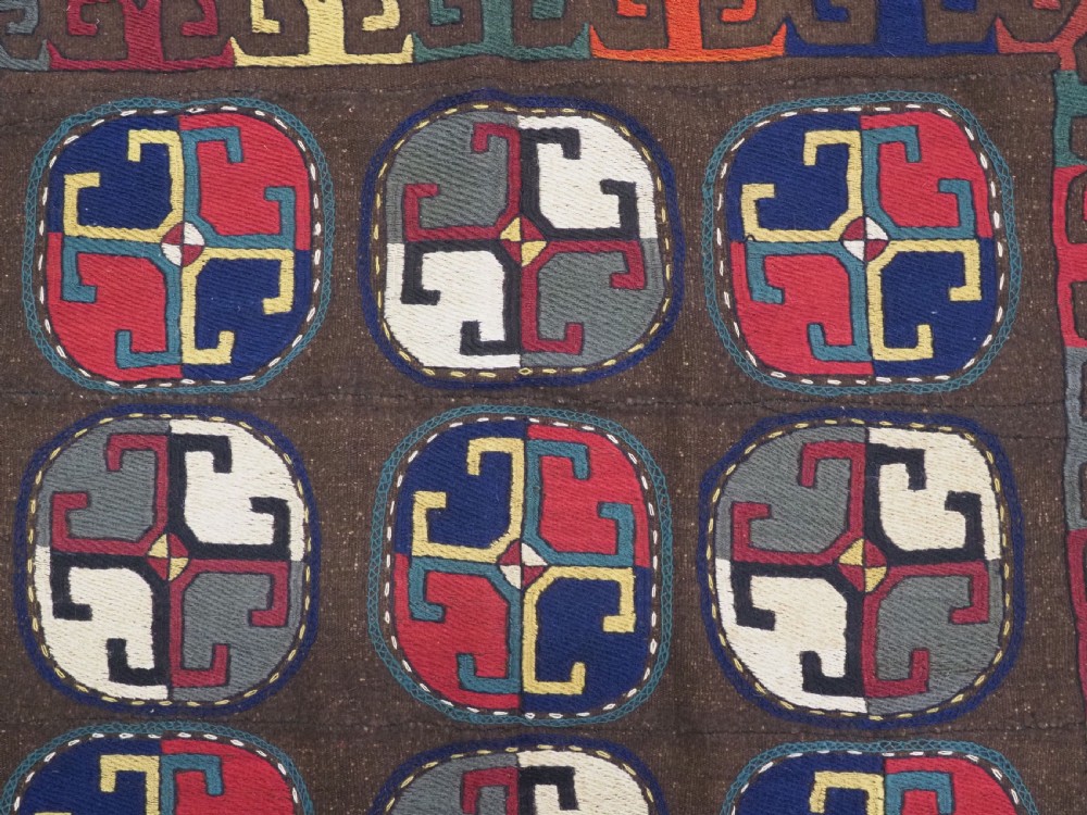 An antique brown camel hair flatweave kilim rug featuring fifteen circular embroidered medallions filled with colourful geometric motifs within a decorative hooked border. View VII