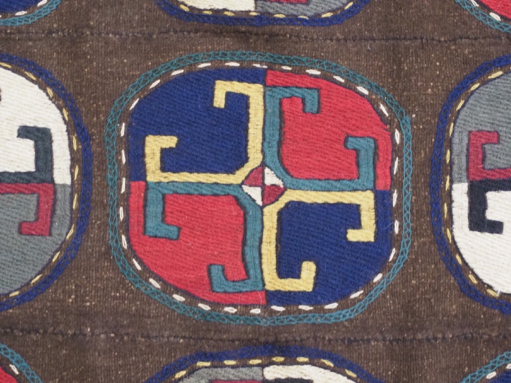 An antique brown camel hair flatweave kilim rug featuring fifteen circular embroidered medallions filled with colourful geometric motifs within a decorative hooked border. View VIII