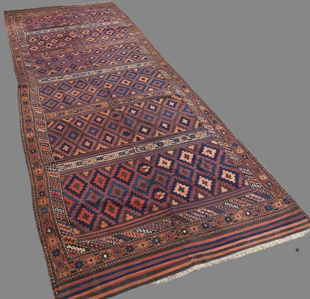 A large flatweave Baluch wool kilim rug featuring two joined panels with geometric diamond bands in terracotta, indigo, and dark brown hues. View II