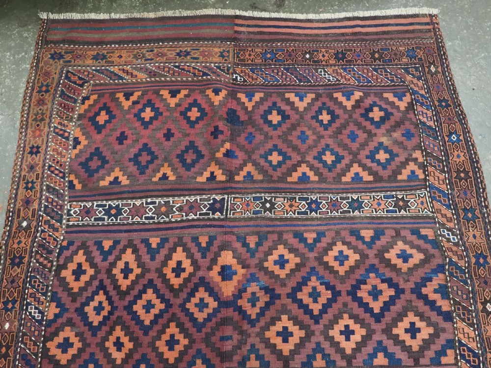 A large flatweave Baluch wool kilim rug featuring two joined panels with geometric diamond bands in terracotta, indigo, and dark brown hues. View III