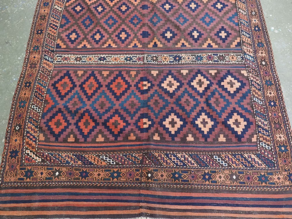 A large flatweave Baluch wool kilim rug featuring two joined panels with geometric diamond bands in terracotta, indigo, and dark brown hues. View VI
