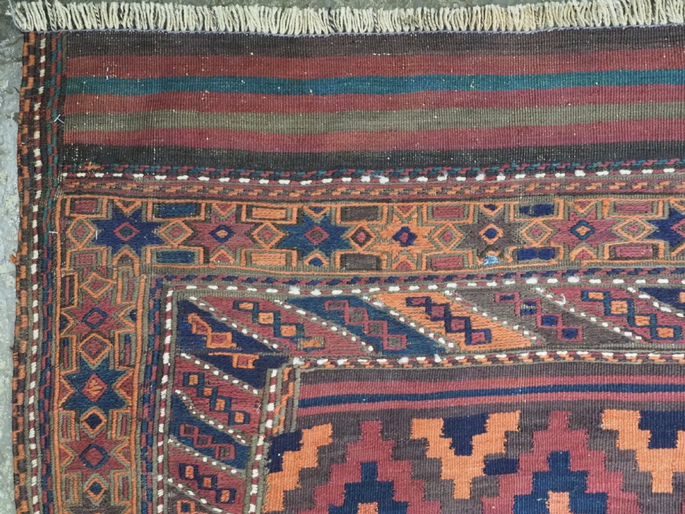 A large flatweave Baluch wool kilim rug featuring two joined panels with geometric diamond bands in terracotta, indigo, and dark brown hues. View VII