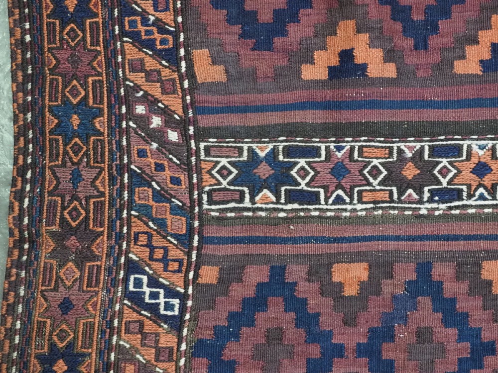 A large flatweave Baluch wool kilim rug featuring two joined panels with geometric diamond bands in terracotta, indigo, and dark brown hues. View VIII