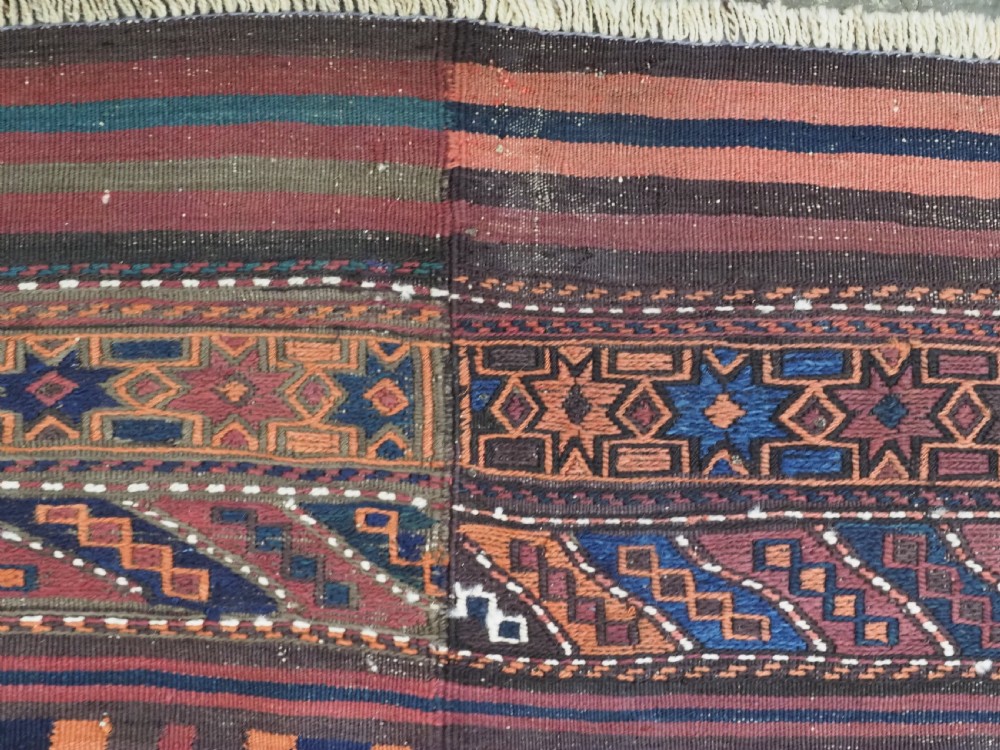 A large flatweave Baluch wool kilim rug featuring two joined panels with geometric diamond bands in terracotta, indigo, and dark brown hues. View IX