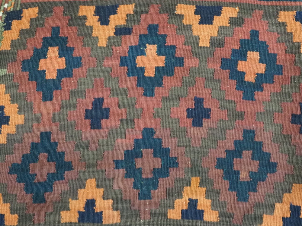 A large flatweave Baluch wool kilim rug featuring two joined panels with geometric diamond bands in terracotta, indigo, and dark brown hues. View X