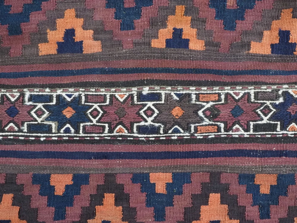 A large flatweave Baluch wool kilim rug featuring two joined panels with geometric diamond bands in terracotta, indigo, and dark brown hues. View XI