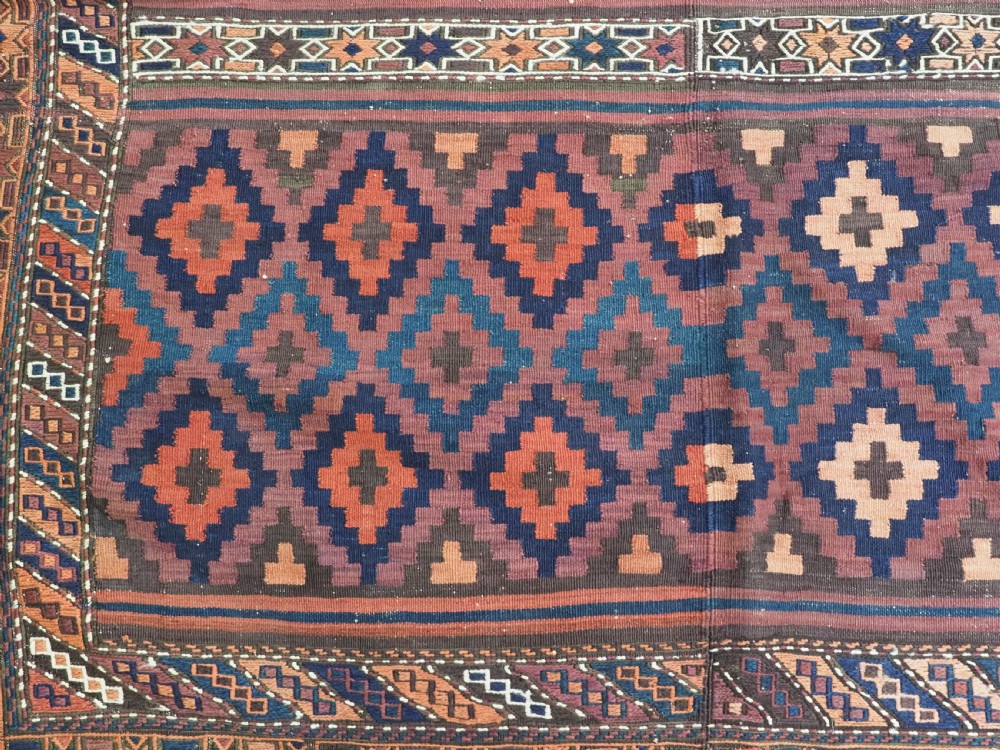 A large flatweave Baluch wool kilim rug featuring two joined panels with geometric diamond bands in terracotta, indigo, and dark brown hues. View XIV