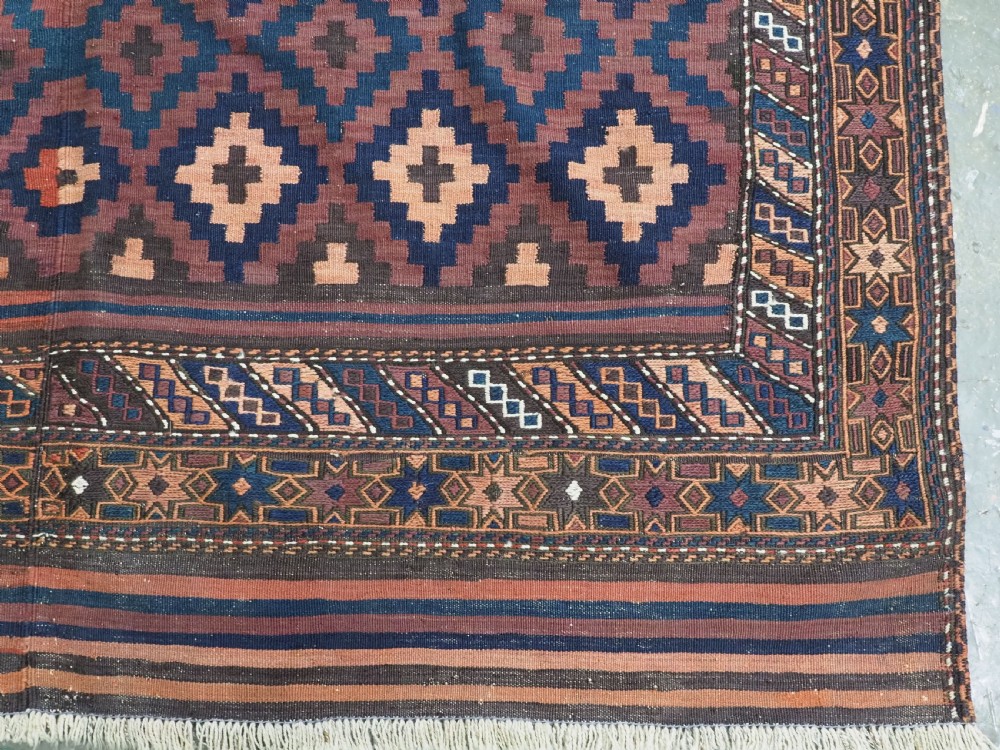 A large flatweave Baluch wool kilim rug featuring two joined panels with geometric diamond bands in terracotta, indigo, and dark brown hues. View XV