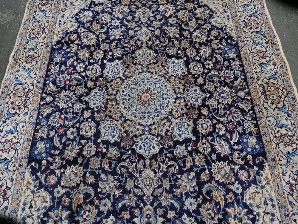 An antique hand-knotted Persian Nain carpet featuring an intricate central medallion in light blue and cream set against a deep navy blue field surrounded by elaborate floral borders. View IV