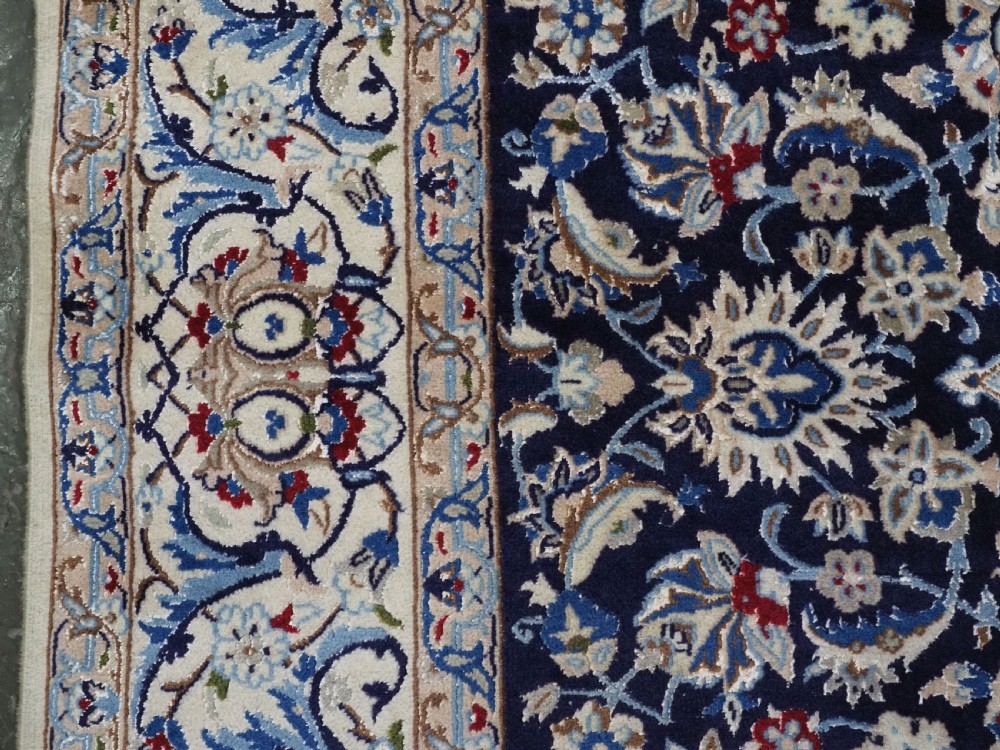 An antique hand-knotted Persian Nain carpet featuring an intricate central medallion in light blue and cream set against a deep navy blue field surrounded by elaborate floral borders. View VII
