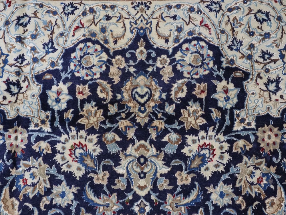 An antique hand-knotted Persian Nain carpet featuring an intricate central medallion in light blue and cream set against a deep navy blue field surrounded by elaborate floral borders. View VIII