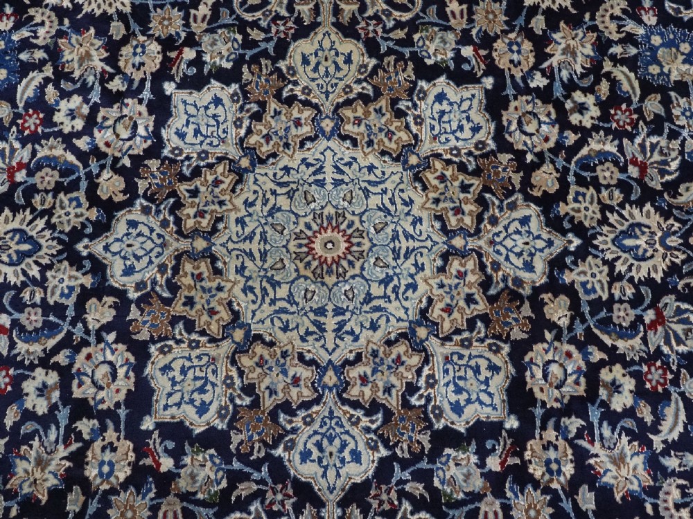 An antique hand-knotted Persian Nain carpet featuring an intricate central medallion in light blue and cream set against a deep navy blue field surrounded by elaborate floral borders. View IX