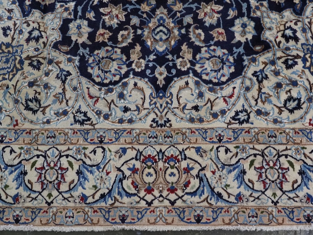 An antique hand-knotted Persian Nain carpet featuring an intricate central medallion in light blue and cream set against a deep navy blue field surrounded by elaborate floral borders. View XI