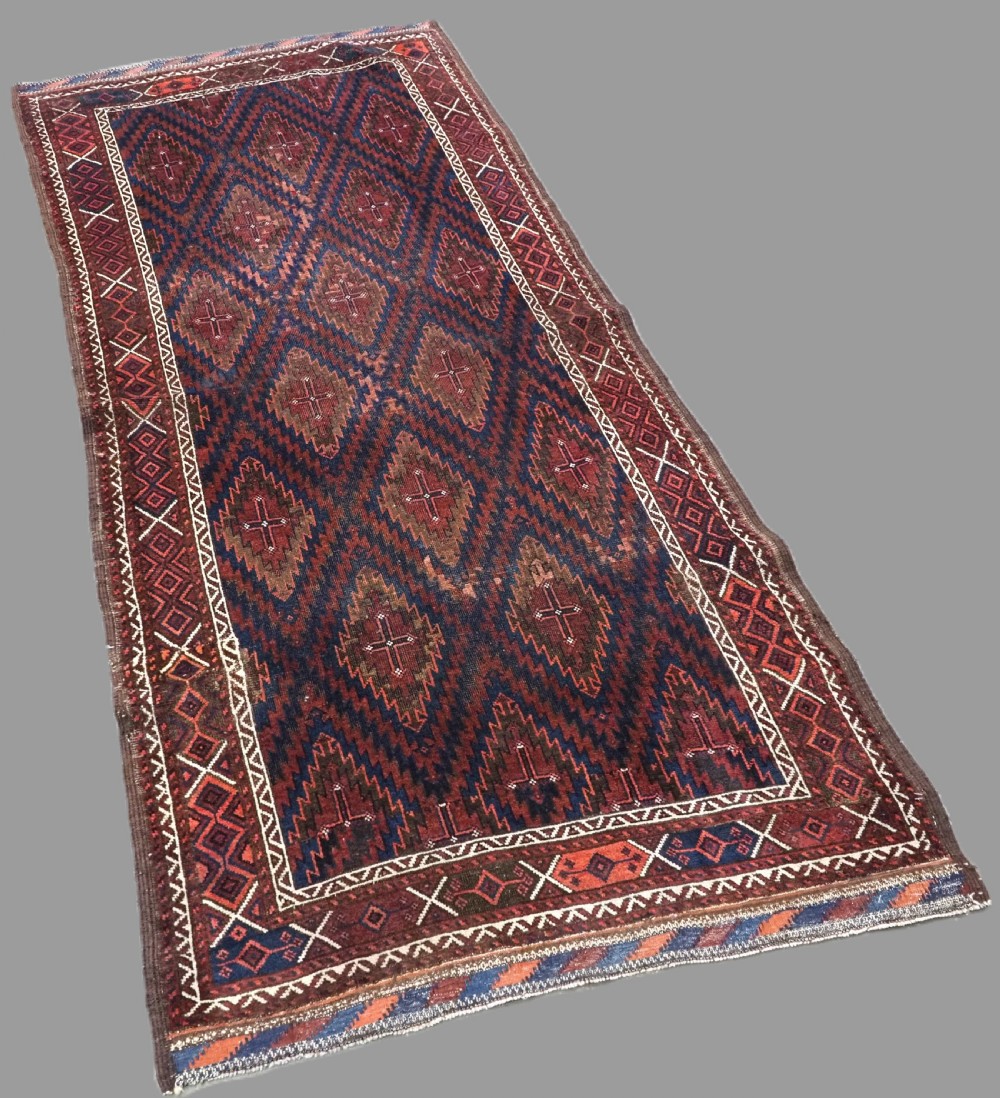 An antique hand-woven Arab Baluch runner rug featuring a dark navy blue and deep red geometric diamond lattice pattern with outer geometric borders. View II
