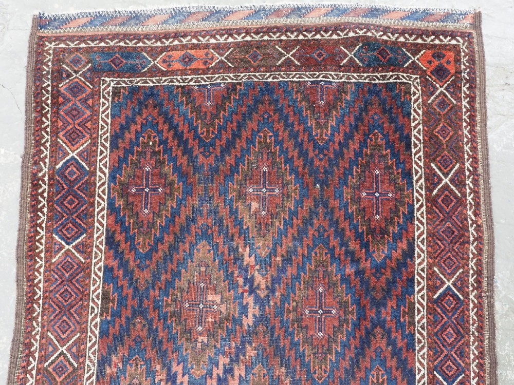 An antique hand-woven Arab Baluch runner rug featuring a dark navy blue and deep red geometric diamond lattice pattern with outer geometric borders. View III