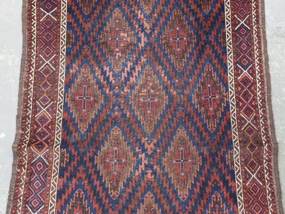 An antique hand-woven Arab Baluch runner rug featuring a dark navy blue and deep red geometric diamond lattice pattern with outer geometric borders. View IV